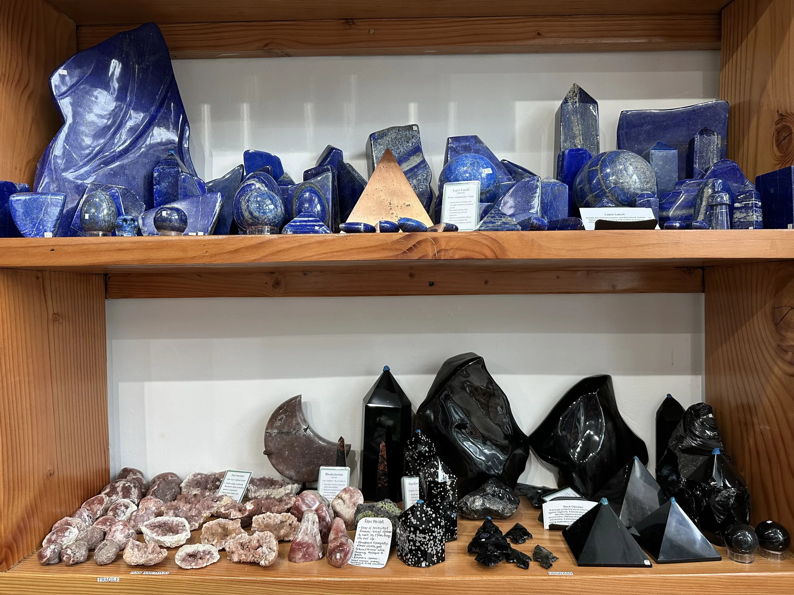 Lapis lazuli and obsidian carvings on wooden shelves