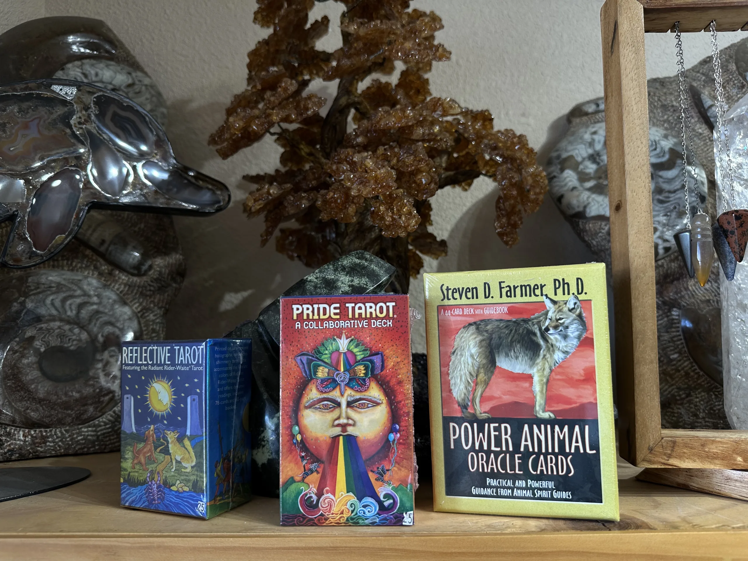 Tarot and oracle card decks on a shelf beside crystals at Stone Room